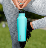 photo of a woman from the legs down in tree pose holding a gloss turquoise corkcicle water bottle in front of her.