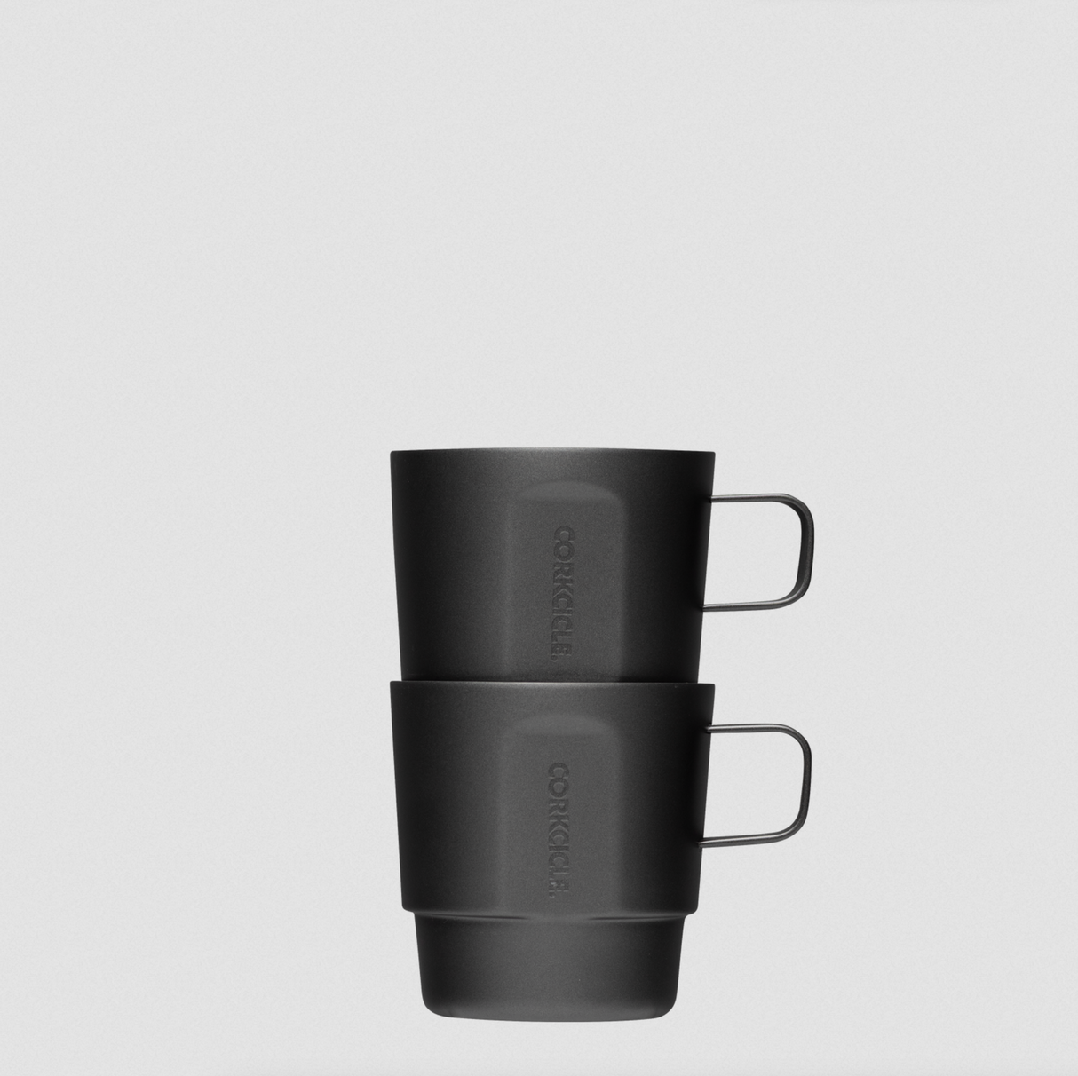 Two black mugs stacked on a light gray background
